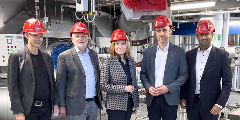 Fünf Gäste mit roten Schutzhelmen, darunter Dr. Wjahat Waraich, stehen in der Klärschlammverbrennungsanlage in Lahe.