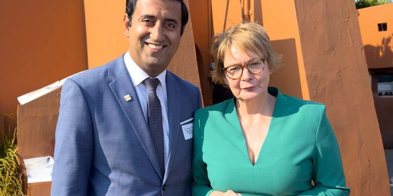 Dr. Wjahat Waraich steht mit Innenministerin Daniela Behrens vor einem Gebäude des Grenzdurchgangslagers Friedland.