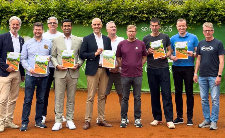 Dr. Wjahat Waraich steht mit Vereinsmitgliedern auf dem Tennisplatz zum 100-jährigen Bestehen von Grün-Weiss Hannover.