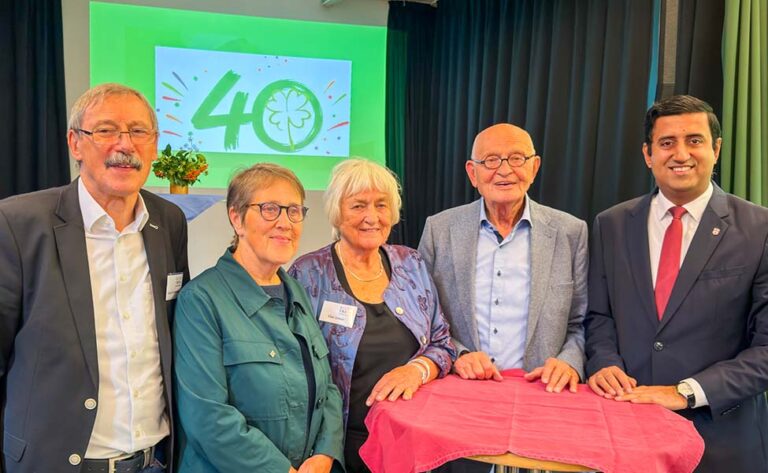 Harry Grunenberg, Vorsitzender der Stadtteilinitiative, steht links und Dr. Wjahat Waraich rechts, dazwischen drei Gäste an einem Stehtisch vor der Leinwand mit dem Jubiläumslogo „40“ des Kulturtreffs Vahrenheide.
